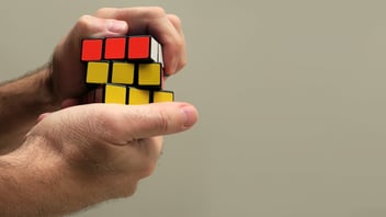 male’s hands trying to solve a rubix cube