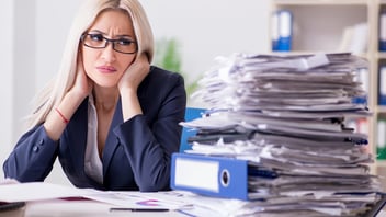 woman staring at the stack of work she has to get done