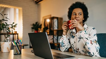woman drinking coffee while working on laptop